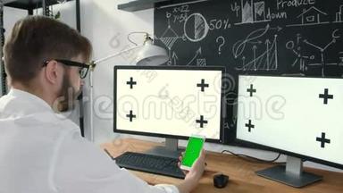 男人拿着平板电脑和手表电视绿色屏幕。 男人手里拿着手机绿屏看电视